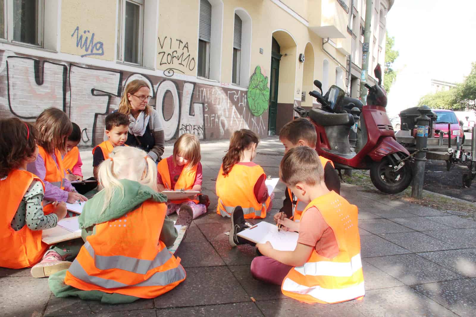 Kinder sitzen auf dem Gehweg und malen
